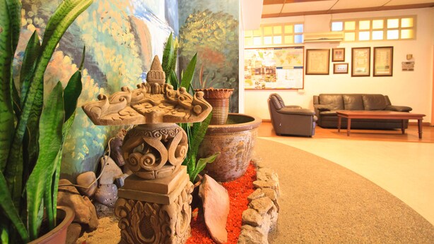 Un vestíbulo con una fuente decorativa, plantas en macetas, un sofá y cuadros en la pared.