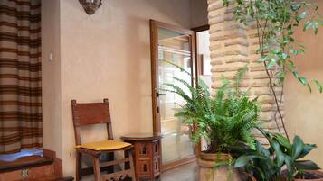 A wooden chair and table near a glass door, with a potted plant beside it.