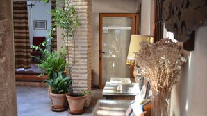 A cozy indoor area with a tiled floor, a wooden door, and a glass table with a lamp and decorative items. - Santa Isabel la Real Hotel (Granada)