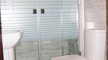 A bathroom with a glass shower enclosure, a toilet, and a sink.