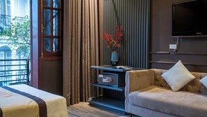 A hotel room with two beds, a sofa, a TV, a vase with flowers, and a window with curtains. - Hanoi Morning Hotel (Hanoi)