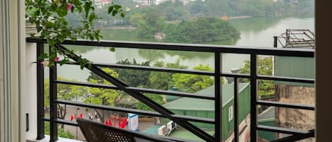 A balcony with wicker chairs overlooking a river and cityscape.
