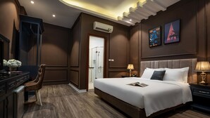 A modern hotel room with a large bed, a desk, and a chair. There is an air conditioning unit on the wall and a door leading to a bathroom. - Hanoi Morning Hotel (Hanoi)