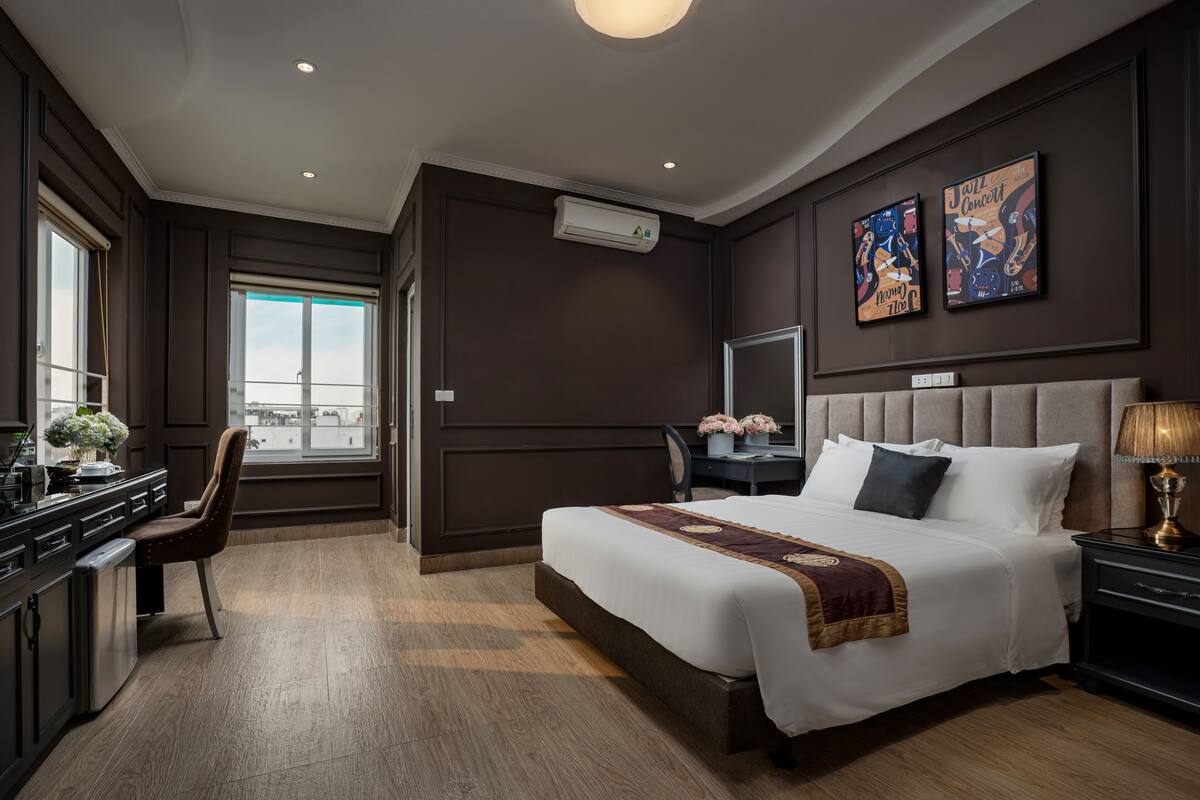 Habitación de hotel con una cama grande, un escritorio, una silla y vistas a la ciudad.