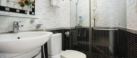 Une salle de bain avec un lavabo blanc, des toilettes et une douche à parois de verre.