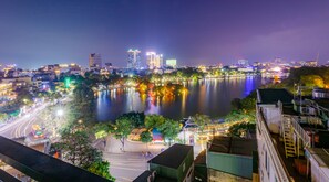 A nighttime cityscape with a river reflecting lights, modern buildings, and a traditional pagoda. - Hanoi Morning Hotel (Hanoi)