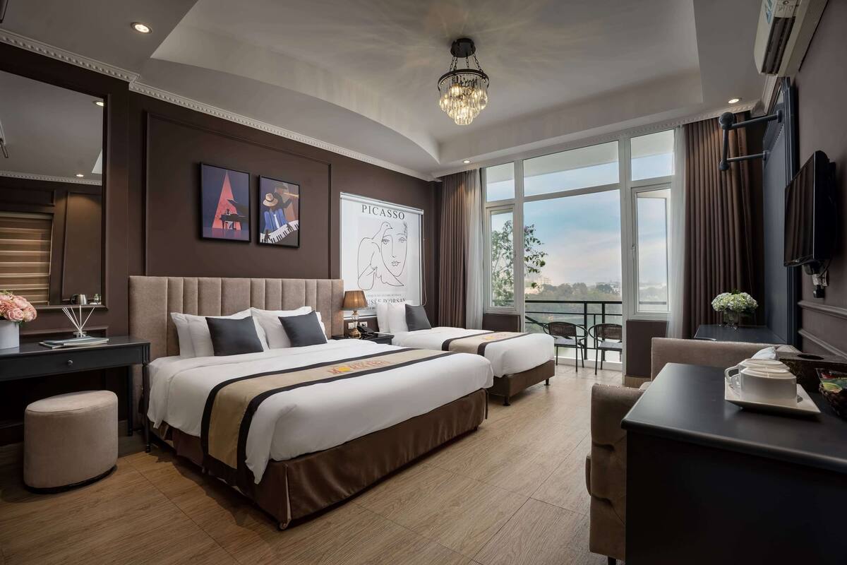 Habitación de hotel moderna con dos camas, un escritorio, una silla y un ventanal con vistas a la ciudad.