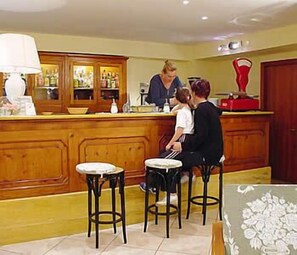 Eine Bar mit Holztresen und Hockern, ein Barista bereitet ein Getränk zu und ein Gast sitzt dort.