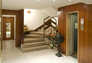 Eine Hottelobby mit Treppe, einer Rezeption und einer Tür mit Rauchverbot-Hinweis.