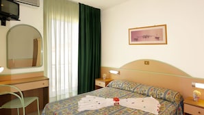 A hotel room with a bed, a desk, a chair, a mirror, a picture on the wall, and a window with curtains. - Hotel Beach 2 (Jesolo)
