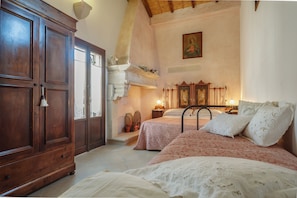 A bedroom with two beds, a wooden wardrobe, and a decorative mirror.