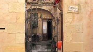 A wrought iron gate with a sign above it reading "Burgstela Dona Puchina".