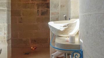 A bathroom with a stone archway, a white sink, a blue towel rack, and a patterned floor.
