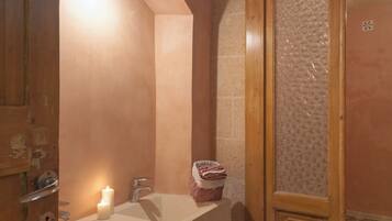 A bathroom with a white sink, a mirror, a wooden door, and a patterned floor.