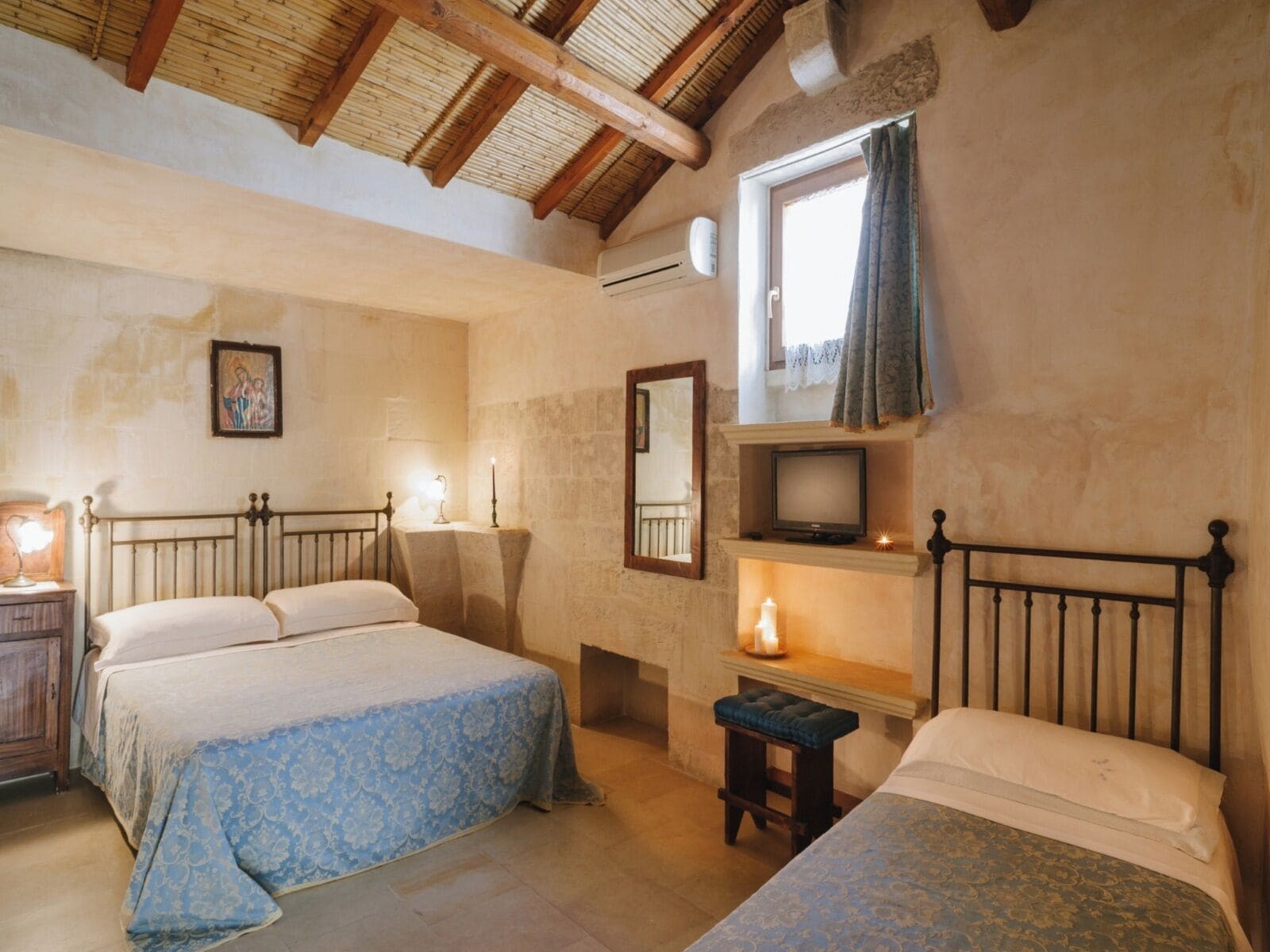 A bedroom with two beds, a television, a small table, and a window with curtains.