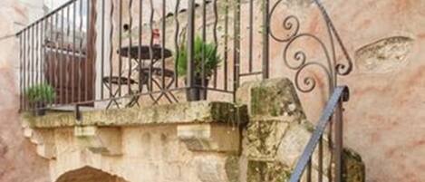 A stone staircase with a wrought iron railing leading to a balcony.