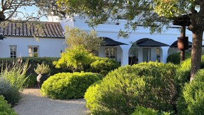 Un jardí ben cuidat amb un camí de grava que condueix a un edifici blanc amb teulada de rajola.