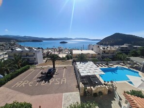 Une vue sur la côte, avec un ciel dégagé, une zone de stationnement signalée par la mention « PARKING UNIQUEMENT », et une piscine.