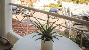 Un balcone con una pianta in vaso, una ringhiera e vista sul mare e sugli edifici.