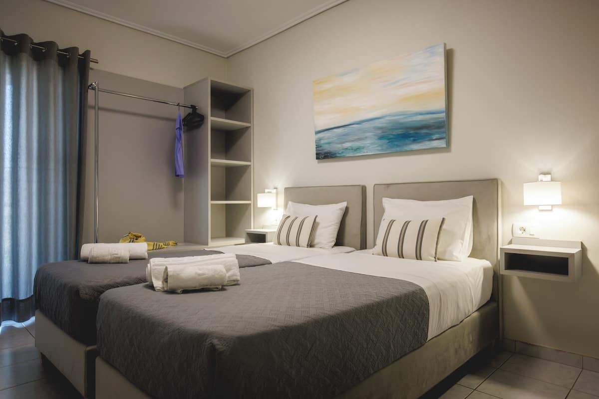 A hotel room with two beds, a large painting, and a wardrobe.