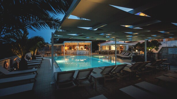 Area piscina con sedie a sdraio, un bar e una piscina.