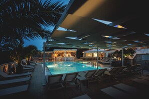 A pool area with lounge chairs, a bar, and a pool.