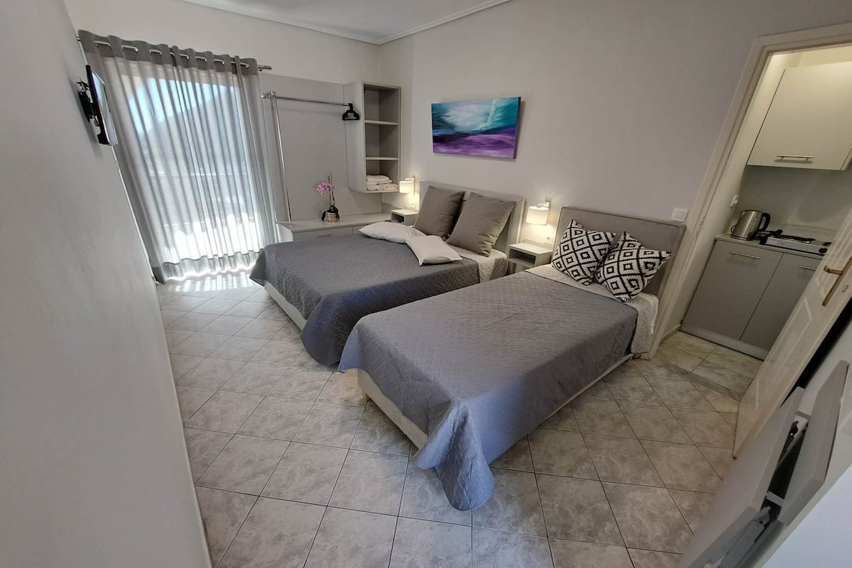 A hotel room with two beds, a bathroom, and a kitchenette.