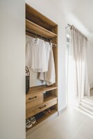 A wooden wardrobe with hanging clothes and a shoe rack.