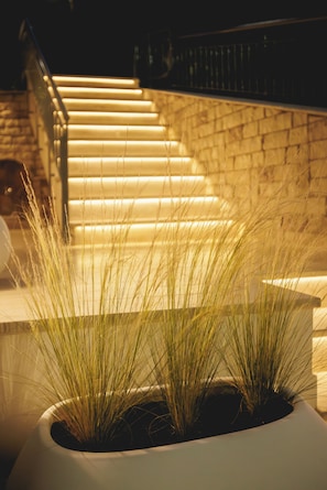 A staircase with illuminated steps, a brick wall, and a planter with grass in the foreground.
