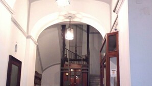 A marble staircase with a wooden door at the bottom, leading to a staircase with a wooden railing. - Amedeo (Naples)