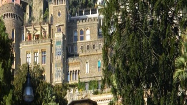 A historic building with multiple architectural styles, including a tower and a pink facade. - Amedeo (Naples)