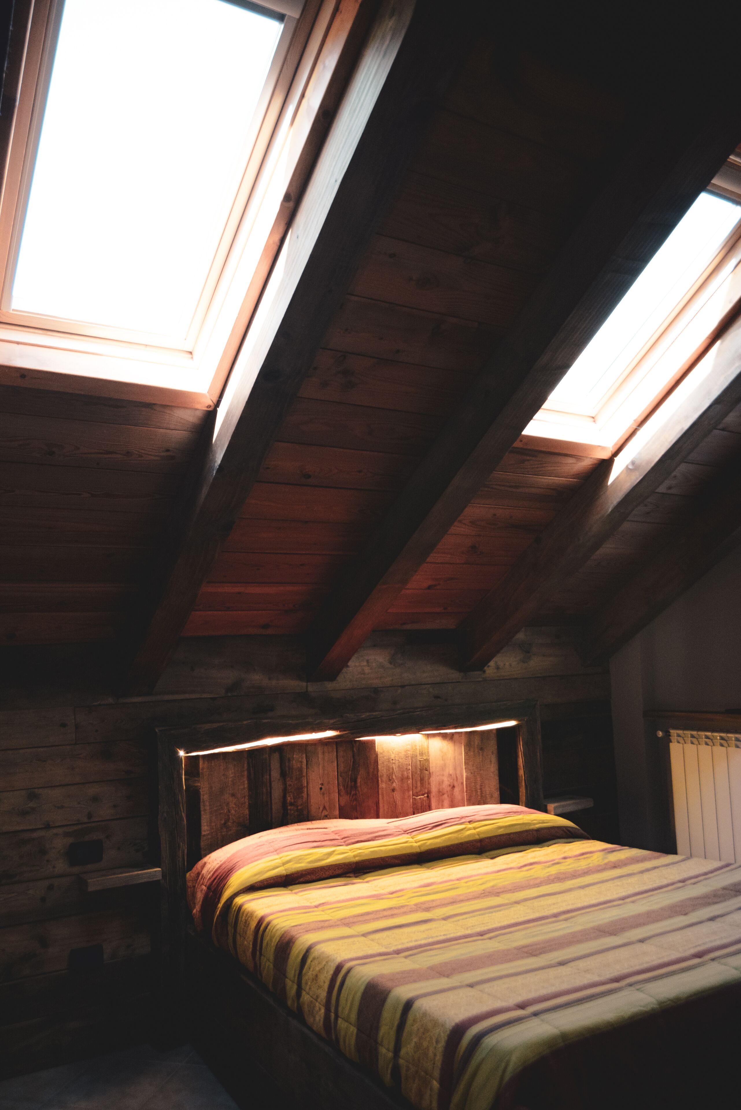 Quarto com teto de madeira e claraboia.
