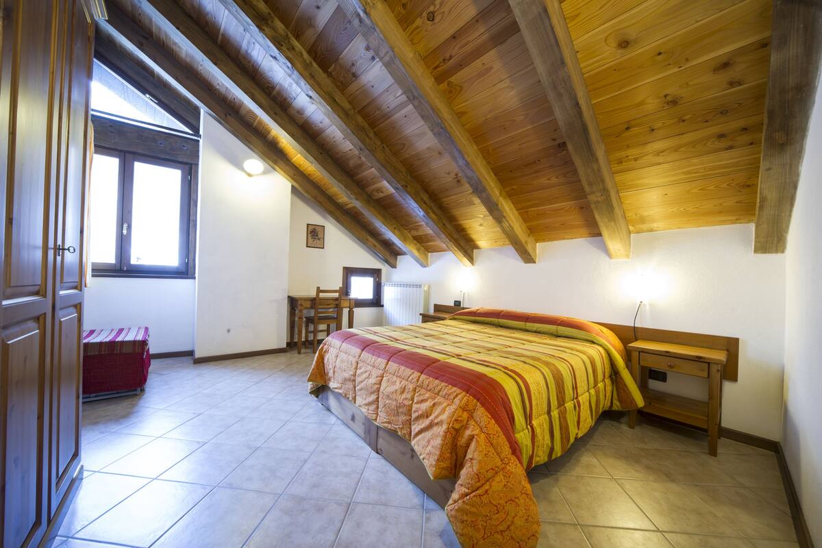 A bedroom with a bed, a desk, and a chair.