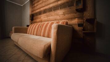 A room with a wooden headboard, a sofa, and a tiled floor.