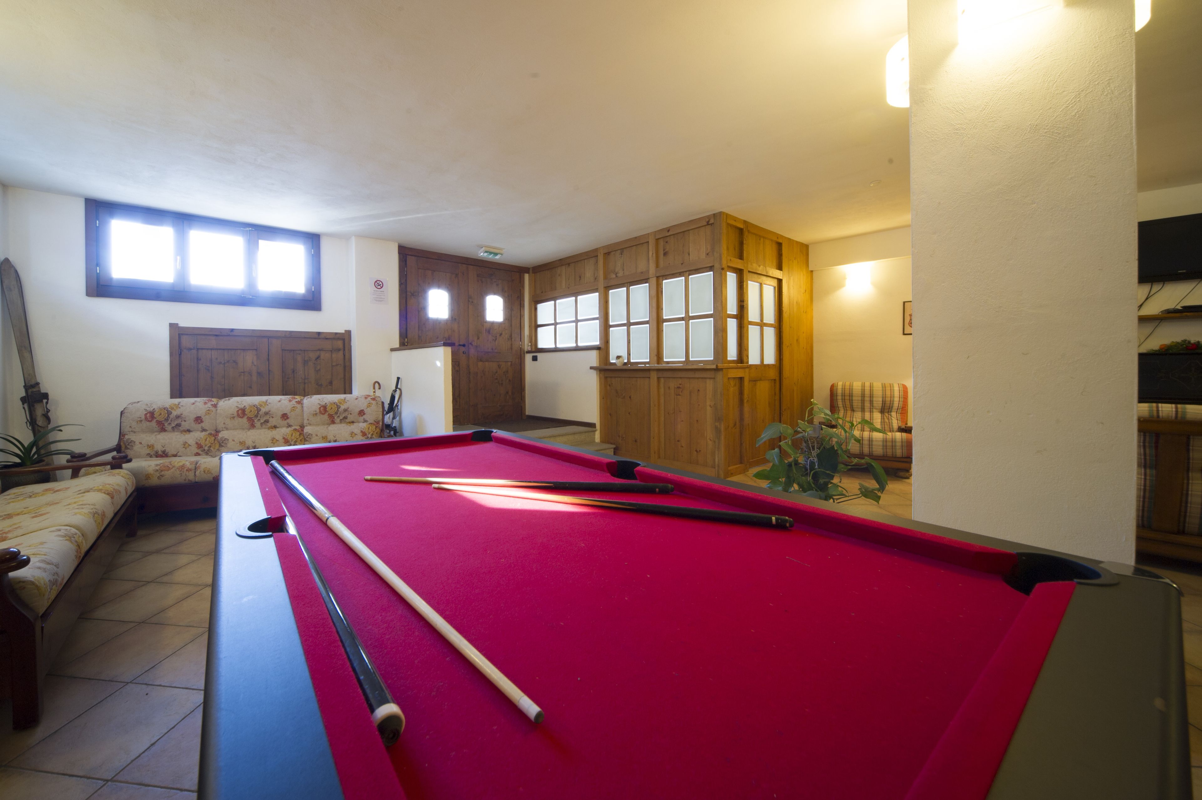 Una mesa de billar en una habitación con un sofá y armarios de madera.