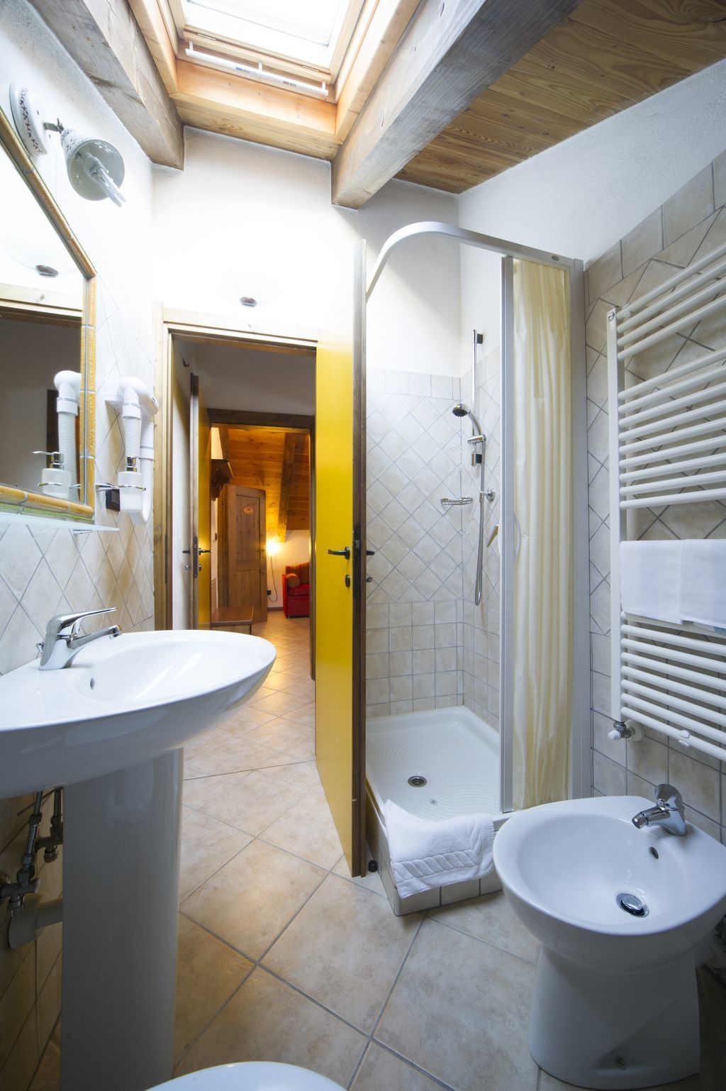 A bathroom with two sinks, a shower, and a skylight.
