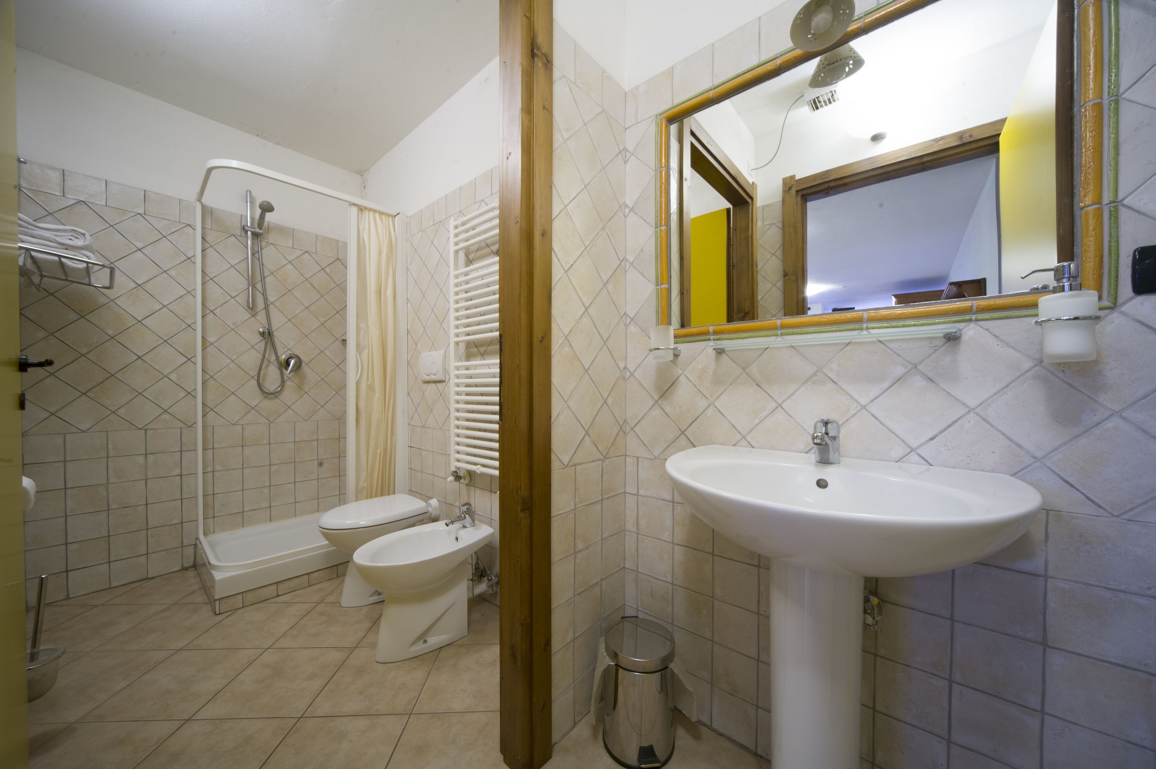 A bathroom with a shower, toilet, bidet, sink, and a mirror.