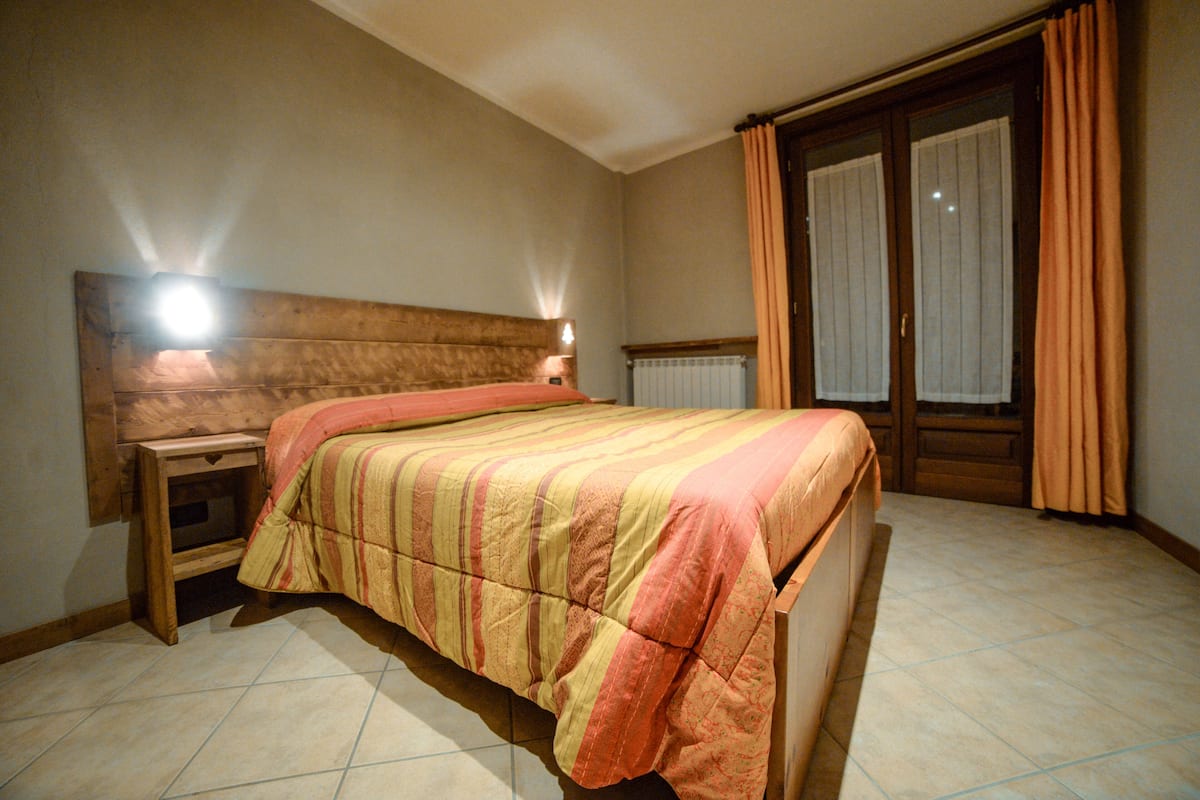A bedroom with a bed, nightstand, and a window with curtains.