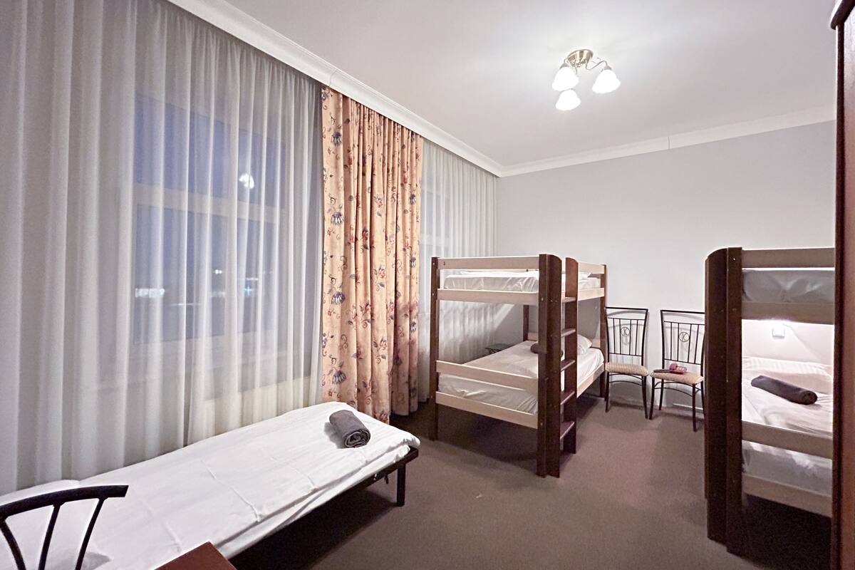 A hotel room with bunk beds, a single bed, a chair, and a small table.