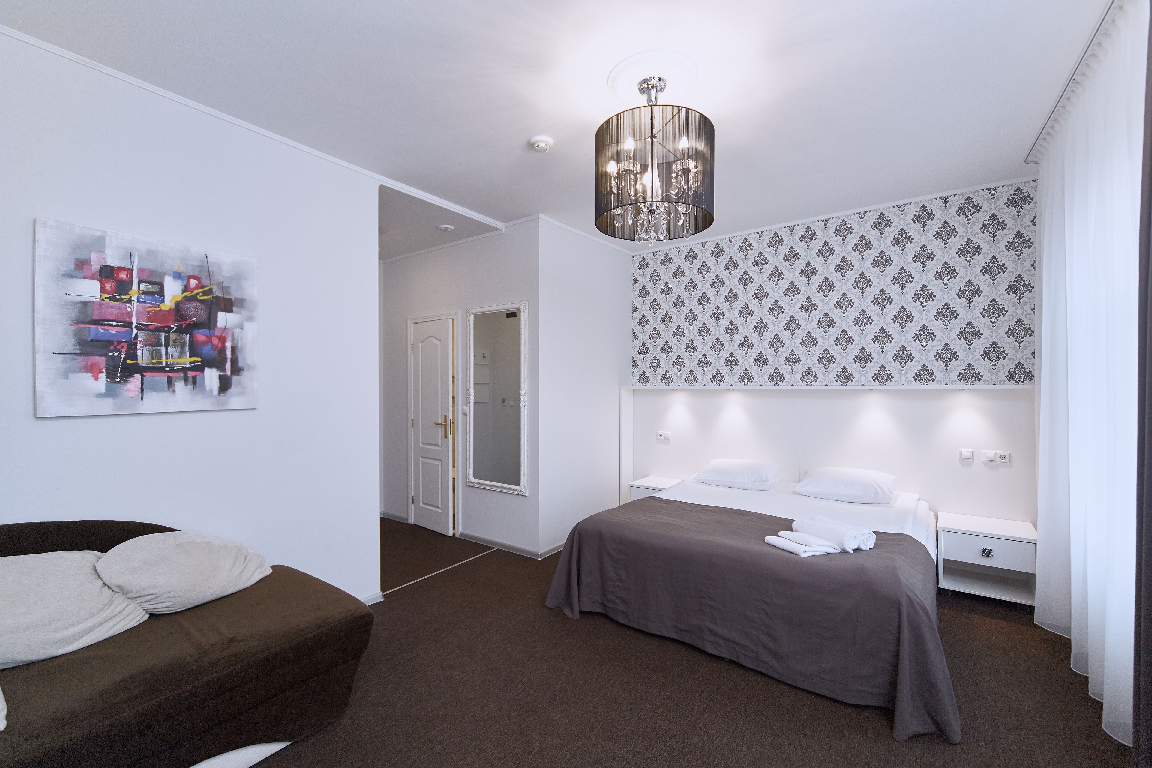 Ein modernes Hotelzimmer mit Bett, Nachttisch und einem großen Fenster.