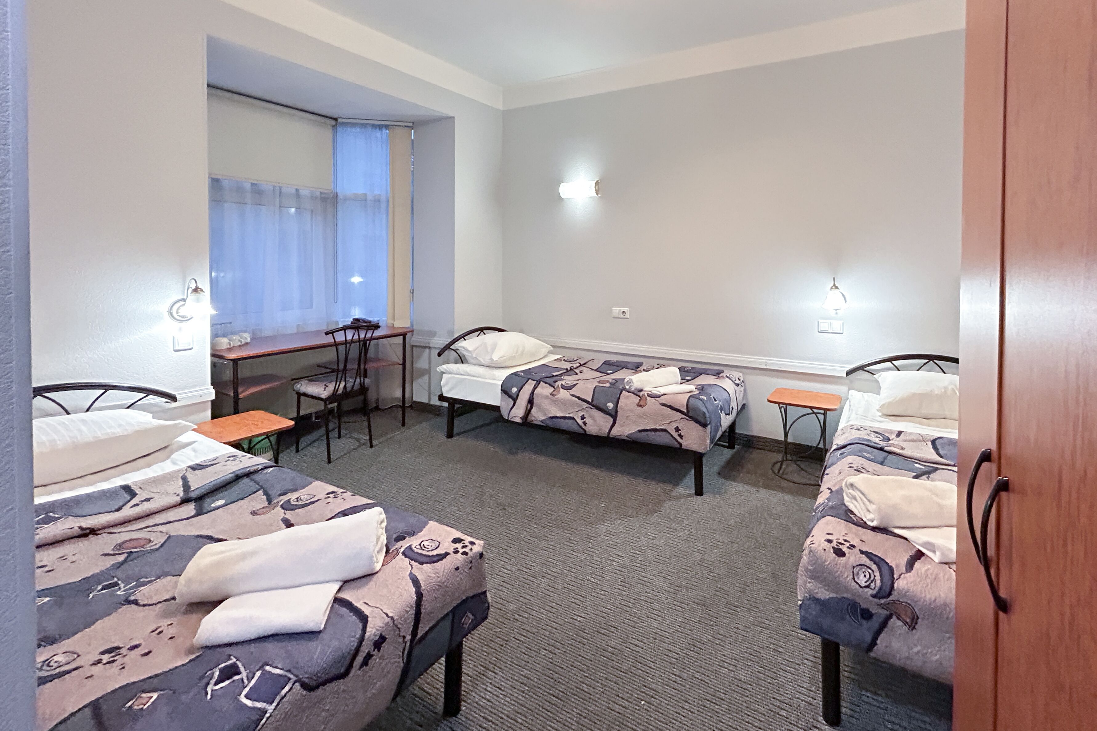 Hotellihuone, jossa on kaksi sänkyä, työpöytä ja tuoli.