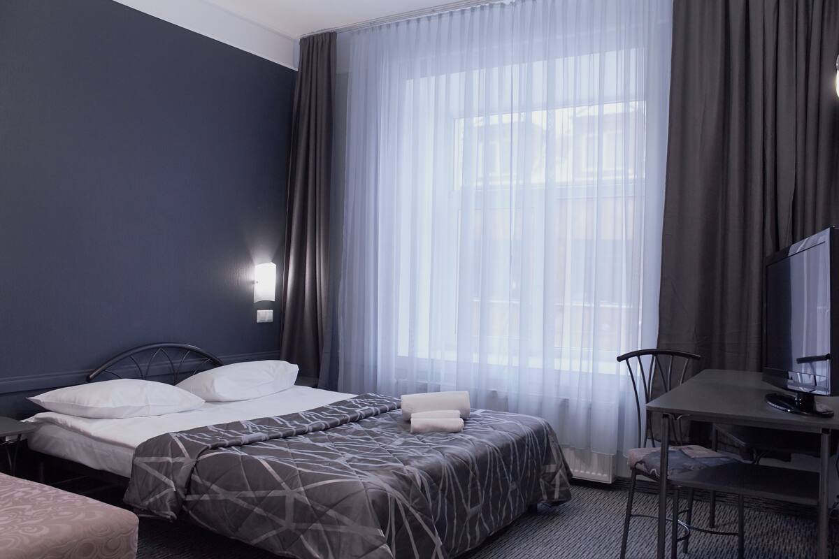 A hotel room with a bed, a desk, a chair, and a TV.
