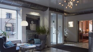 A modern lobby with a seating area, a large window, and a chandelier. - Hotel OK (Riga)