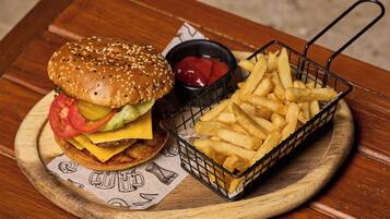 En tallerken med en hamburger med salat, tomat og ost, en portion pommes frites og en lille beholder ketchup.