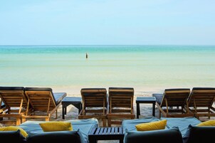 Vista de una playa con sillones de madera y arena.