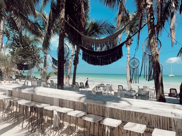 Pantai di sekitar, pasir putih, kursi berjemur, dan handuk pantai