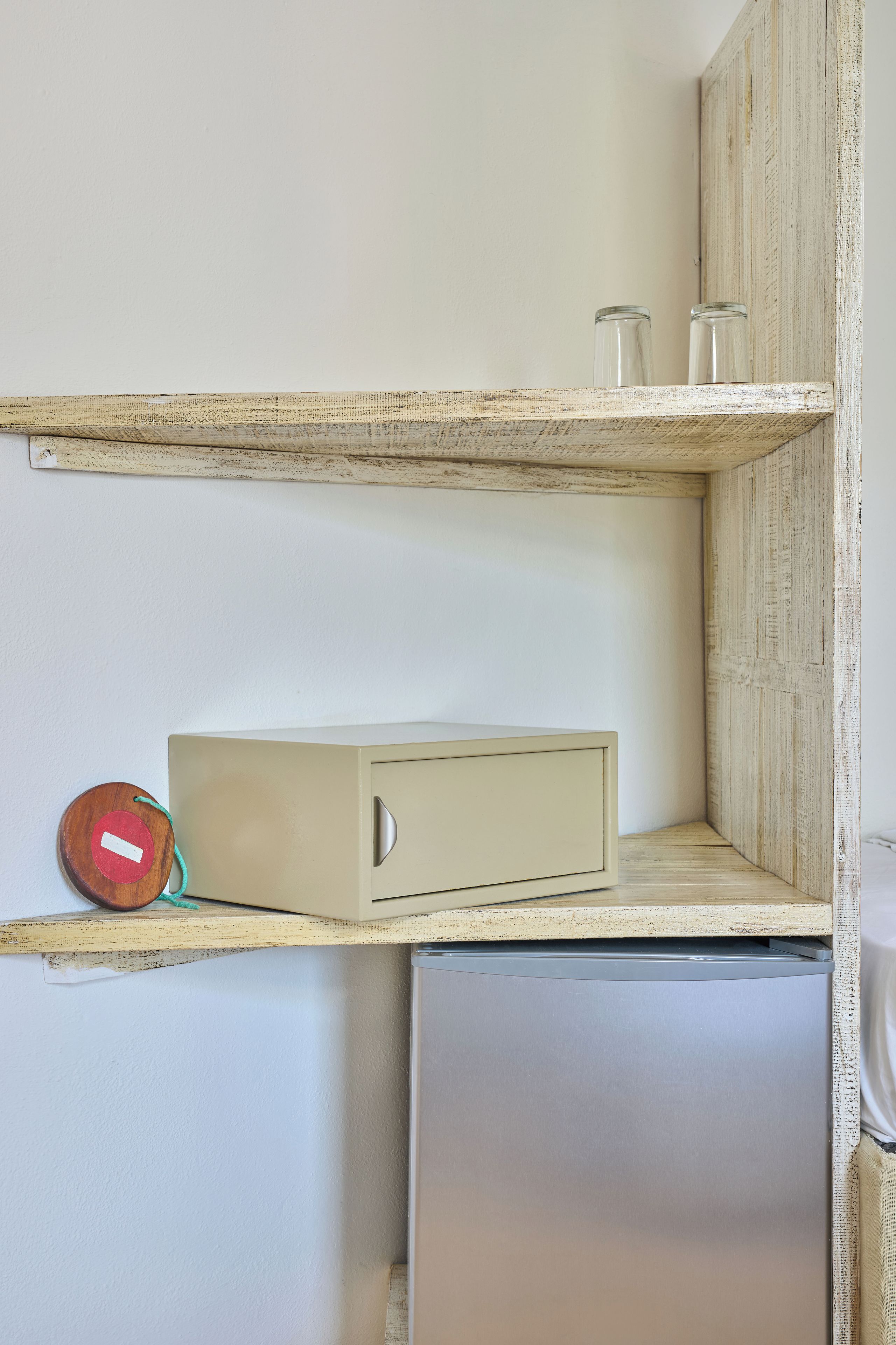 Una kitchenette compacta con un refrigerador empotrado, un mueble pequeño y una estantería con un tarro de vidrio.