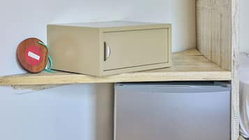 Una kitchenette compacta con un refrigerador empotrado, un mueble pequeño y una estantería con un tarro de vidrio.