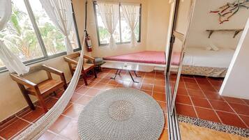 A room with a hammock, a round woven mat, a bed, and a bench.