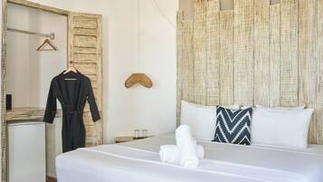 Habitación de hotel con cama, espejo, bata, toalla y pared con textura.
